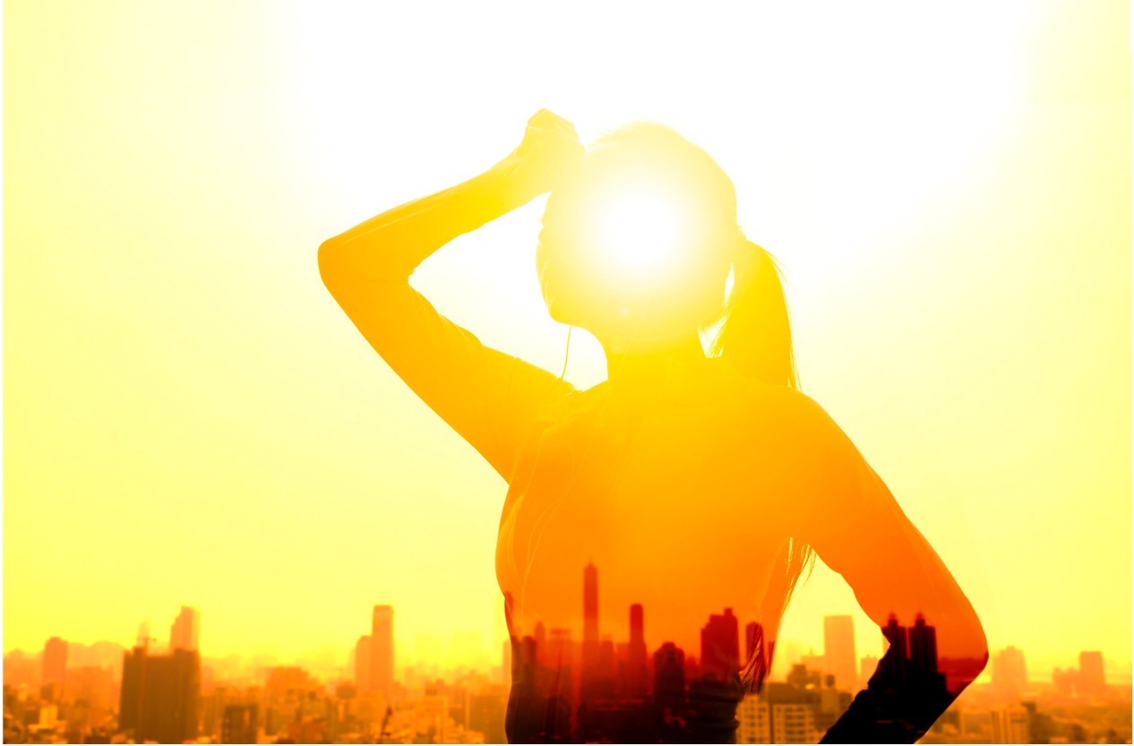 Woman standing in sunlight in front of a city